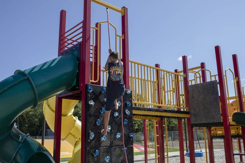 Jeune fille grimpant dans un jeu de parc extérieur.