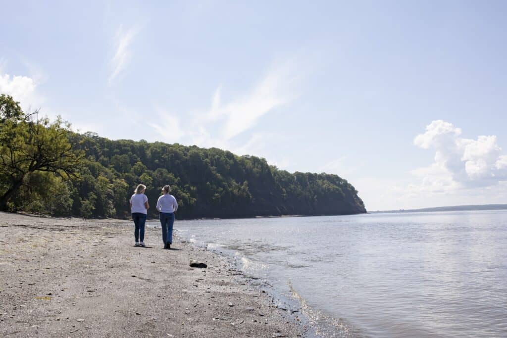 Deux personnes marchent sur la plage ensoleillée.