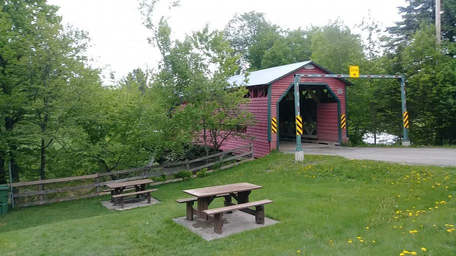 Pont couvert rouge avec tables de pique-nique.