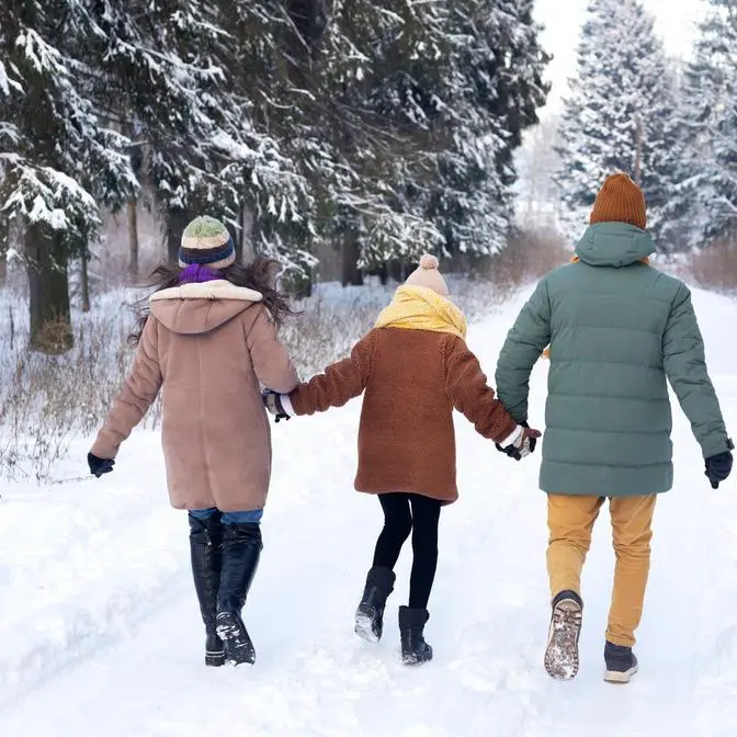 Trois personnes marchant dans la neige, forêt d'hiver.