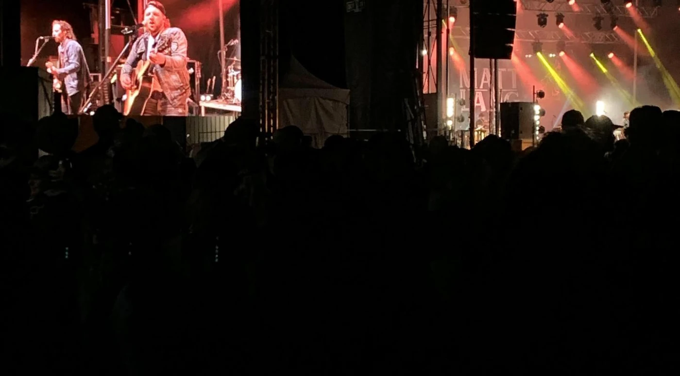 Concert en direct avec écran géant et lumières rouges.