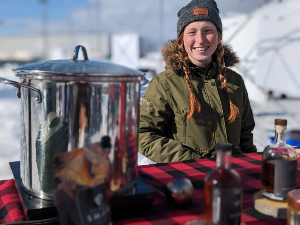 Personne souriante avec marmite en extérieur enneigé.