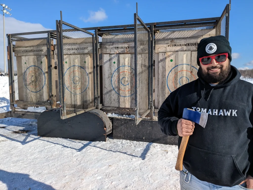 Homme souriant tenant une hache, cibles derrière lui.