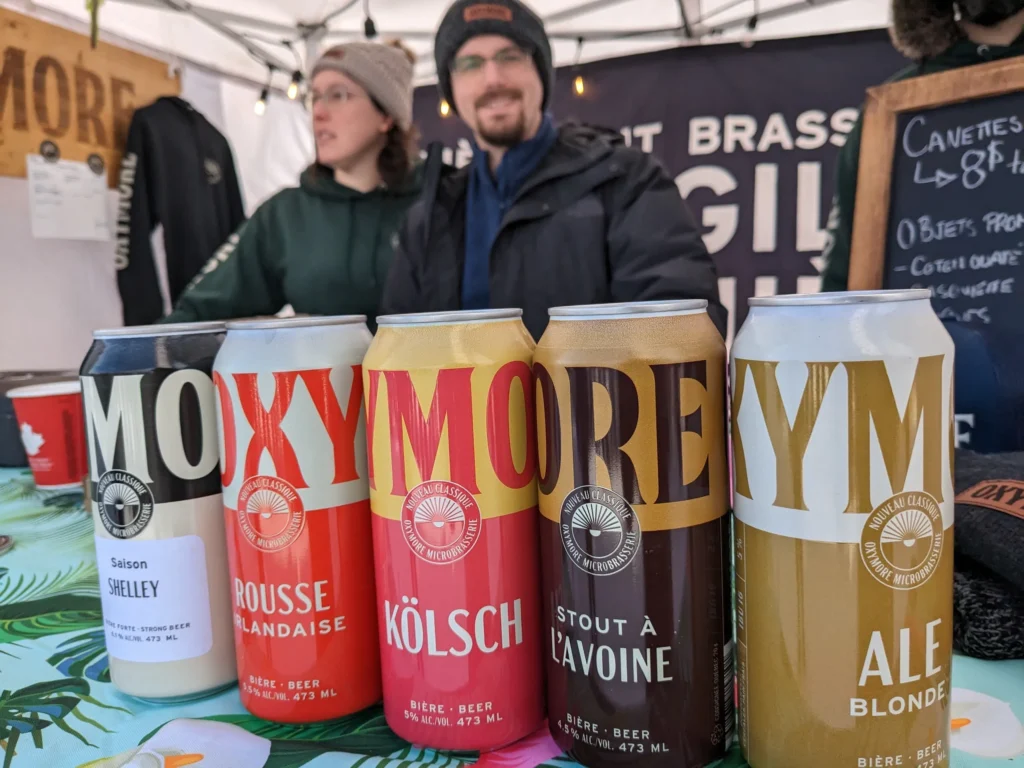 Cinq canettes de bière artisanale sur une table.