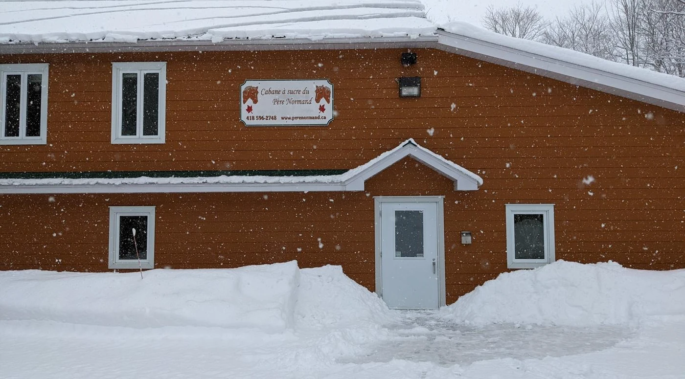 Façade enneigée d'une cabane à sucre.
