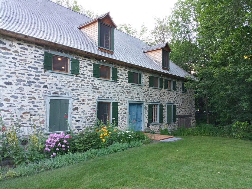 Maison en pierre avec jardin fleuri, été.