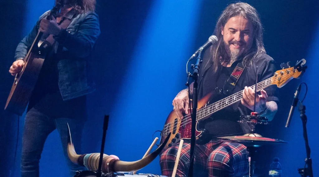 Musiciens sur scène jouant de la guitare et basse.