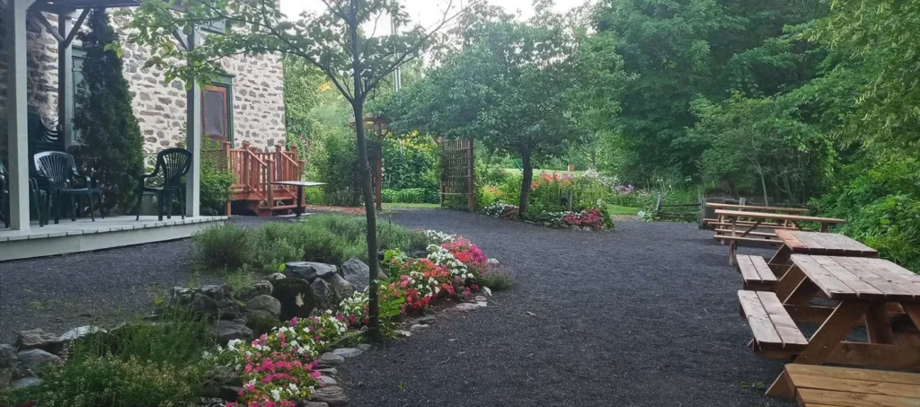 Jardin avec fleurs et mobilier extérieur rustique.