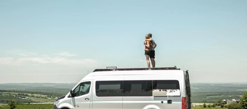 Couple debout sur un van blanc, vue panoramique.