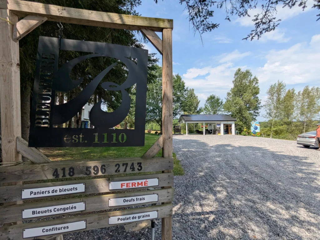 Enseigne bleuetière fermée avec stationnement et bâtiment.