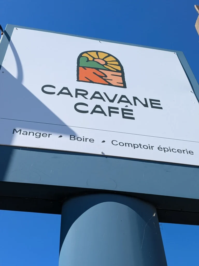 Enseigne Caravane Café sous ciel bleu.