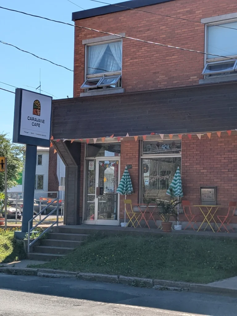 Entrée de café avec enseigne et terrasse extérieure.