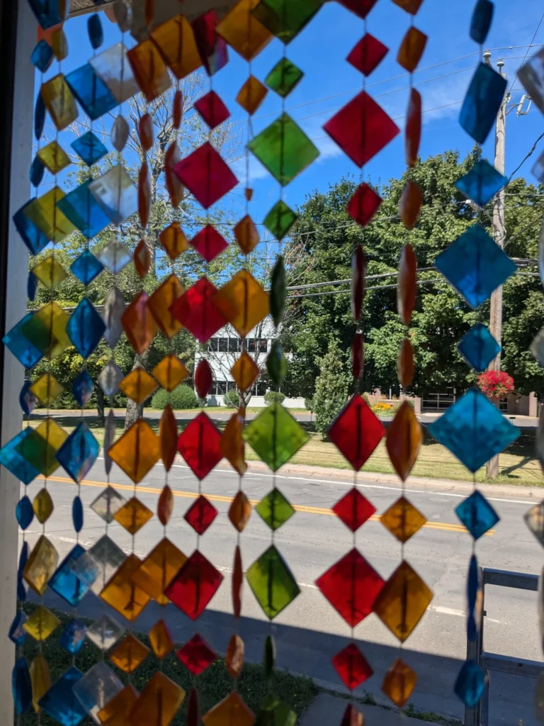 Rideau de perles colorées devant une rue ensoleillée.