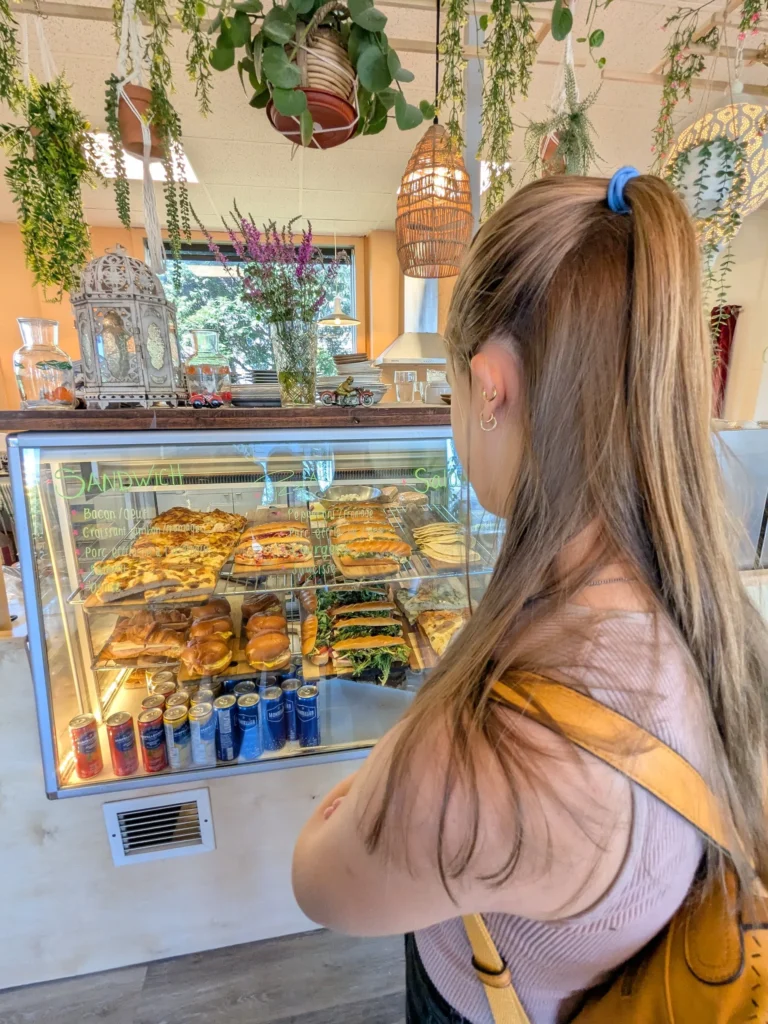 Femme regardant vitrine pâtisserie sandwiches.