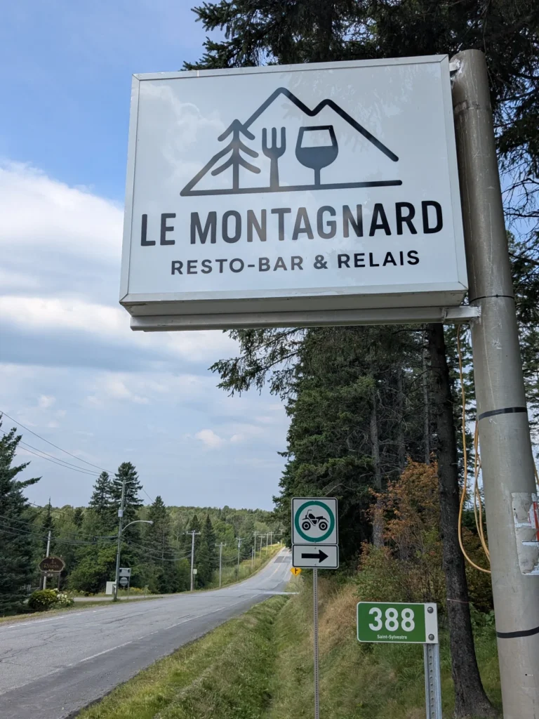 Enseigne Le Montagnard près d'une route forestière.