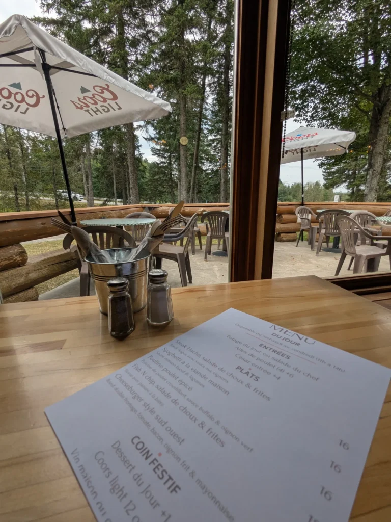Table de restaurant avec menu et terrasse boisée.