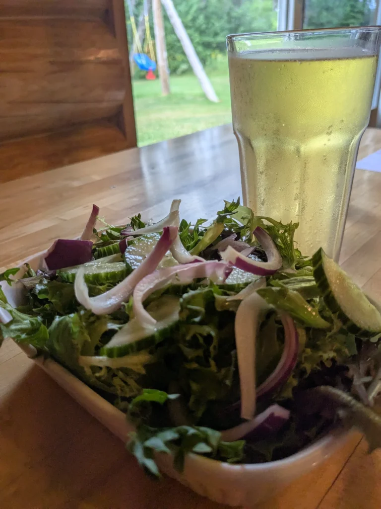Salade verte et verre de boisson claire.