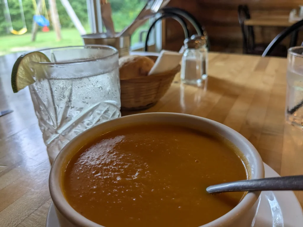 Soupe orange sur table en bois, extérieur flou.