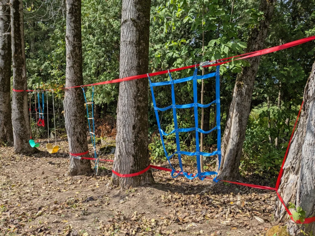 Parcours d'obstacles en forêt avec filets et cordes.