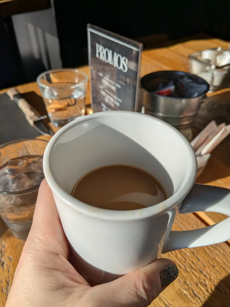 Tasse de café tenue près d'une table.