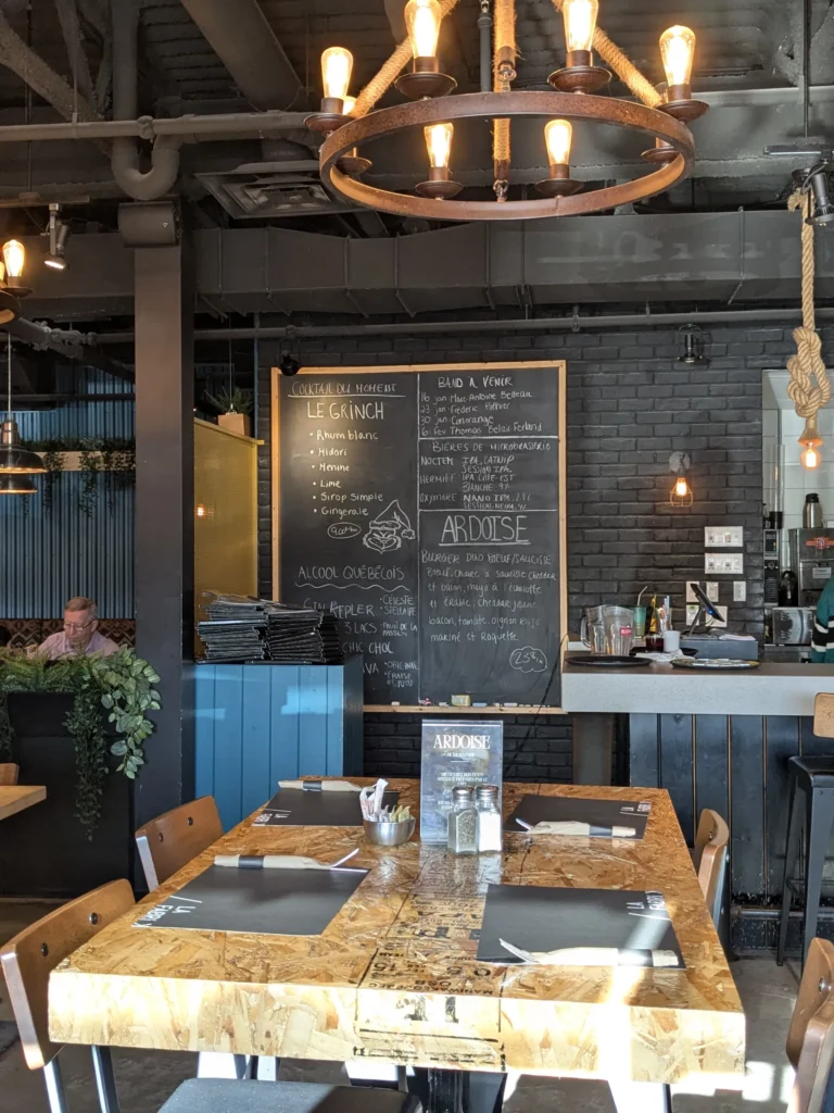 Restaurant avec ardoise, table en bois, éclairage industriel.